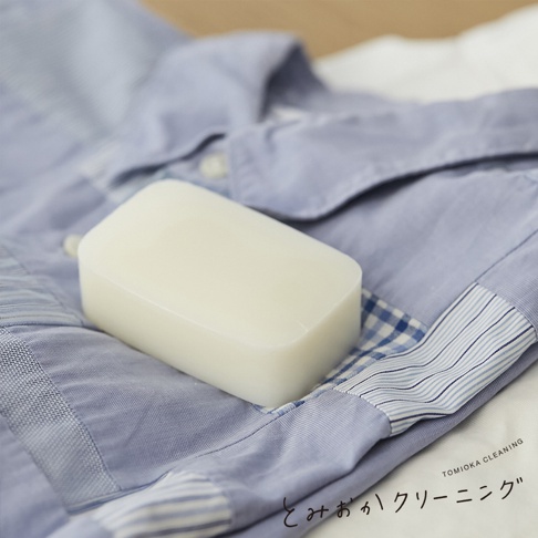 一塊白色長方形洗衣皂放在藍色條紋和格紋布料襯衫的領口處。