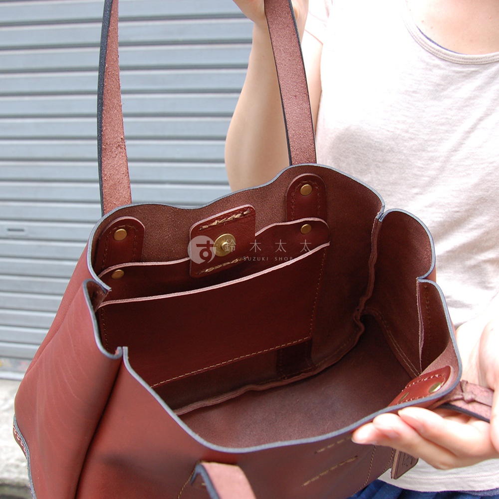 職人手作皮革仕女托特包 T-10，展示深棕色皮革內裡，有兩個內袋和一個金屬磁扣，手提帶為皮革材質。