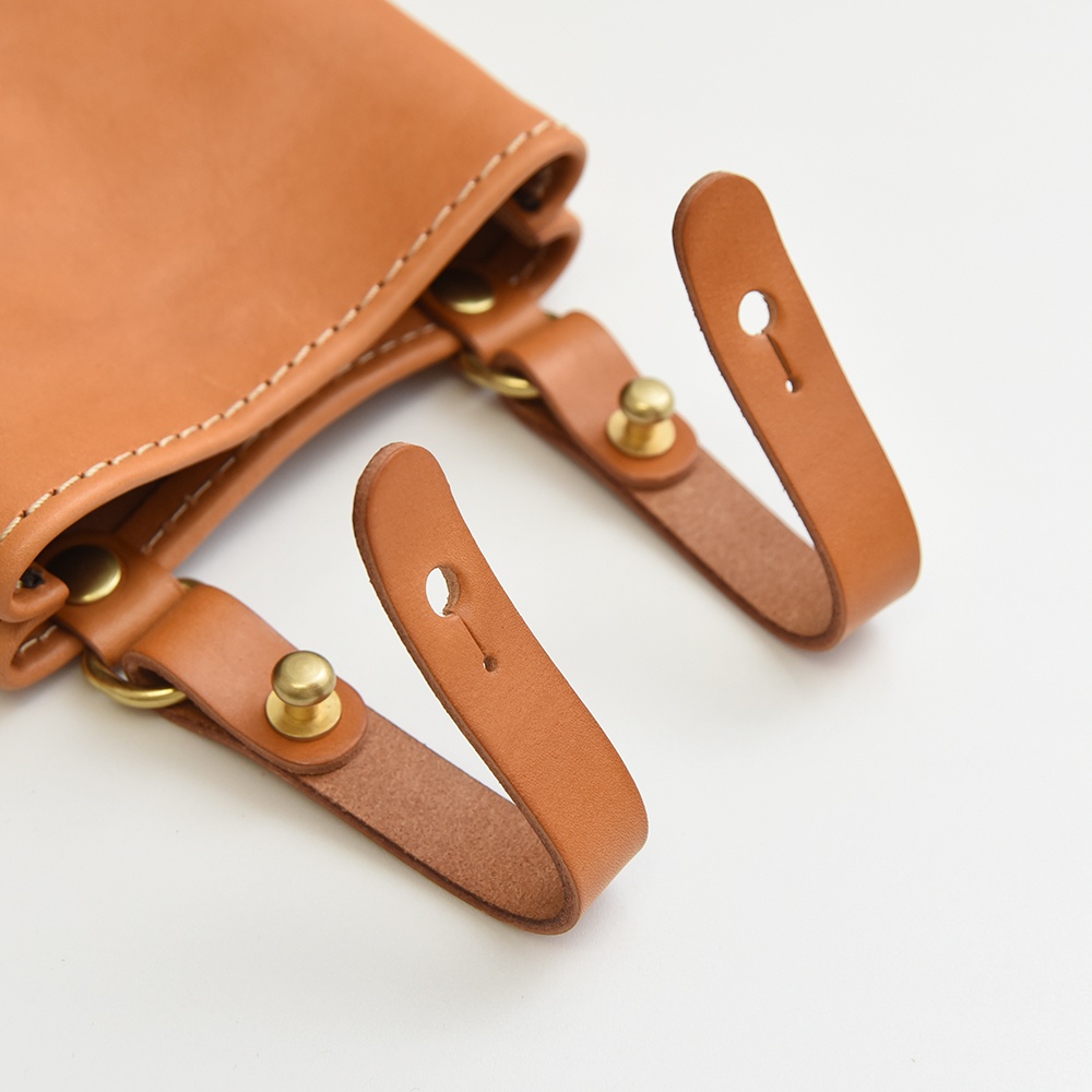 職人手作皮革多用途工作用腰袋 E-27，採用天然皮革材質，呈現溫潤的焦糖棕色，搭配黃銅色五金配件，設計簡約實用。