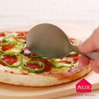 銀色金屬切切分食匙，刀緣帶有鋸齒，正用於切分一片淋有番茄醬、起司、青椒和香腸的披薩，披薩放在木質砧板上。