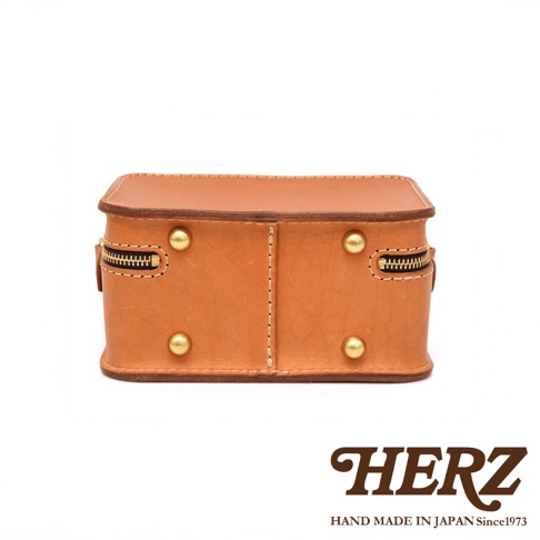 日本HERZ品牌標誌及標語「HAND MADE IN JAPAN Since1973」，搭配一個手工皮革小方包的正面視角