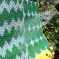 防水 PP 戶外室內兩用收納野餐墊，綠色與白色交織的葉子圖案，材質表面呈現細密的編織紋理，水柱正沖洗在墊子上，展現其防水特性。