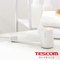 一個白色的TESCOM負離子吹風機，放置在白色桌面上，背景是白色毛巾和瓶子。