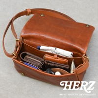 職人手作皮革Organ斜背包，駝棕色，皮革材質，包內展示有皮夾、卡夾、筆等物品。