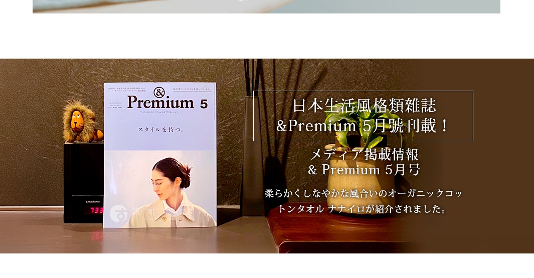 一張深色背景的宣傳圖，左側擺放著一本標示為 5 月號的 &Premium 日本生活風格雜誌，旁邊有一隻小型獅子玩偶與一個棕色花瓶，右側文字宣傳該雜誌 5 月號刊登了日本 TT 毛巾旗下柔軟的泉州上質印度有機棉毛巾系列產品。
