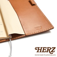 職人手作皮革輕便記事本書套，淺棕色皮革，內含筆記本，書套右側壓印有品牌標誌。