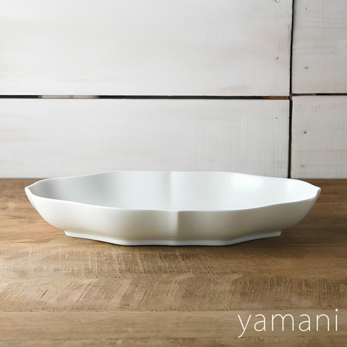 Tsudoi 淡青白釉美濃燒輪花長盤，一個白色、輪花造型的長方形陶瓷盤，置於木質桌面，背景為白色木板牆。