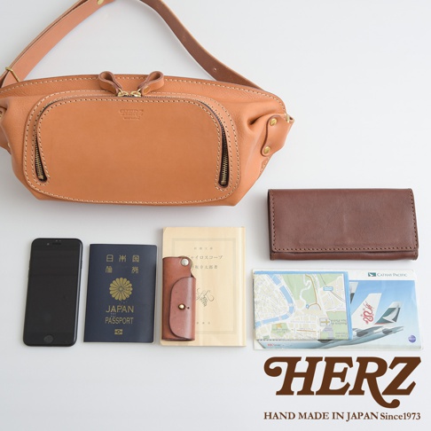 日本HERZ職人手作皮革拉鍊旅行斜背包，搭配手機、日本護照、皮夾、地圖、機票，展現質感與實用性。