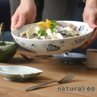 白色陶瓷大圓深碗，碗身繪有藍色海龜、小魚、貝類和雲朵圖案，盛裝著生蠔、檸檬片和香草。