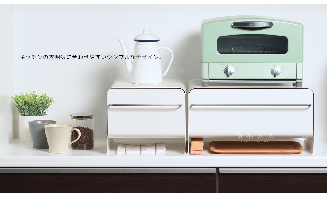 白色抽屜式收納櫃，附有銀色金屬把手，櫃面簡潔，頂部擺放著白色琺瑯壺和薄荷綠烤箱，櫃體下方空間可放置物品，材質為塑膠或木質。