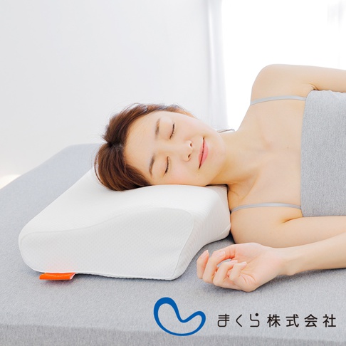白色護頸止鼾枕，表面有細緻紋理，為波浪造型，適合側睡或仰睡。枕頭左側有一個橘色標籤。