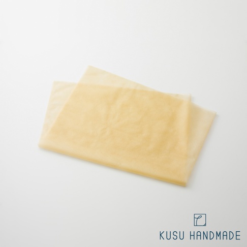 兩件淺黃色、半透明的薄布料，堆疊在白色背景上，左上角為產品品牌標誌。