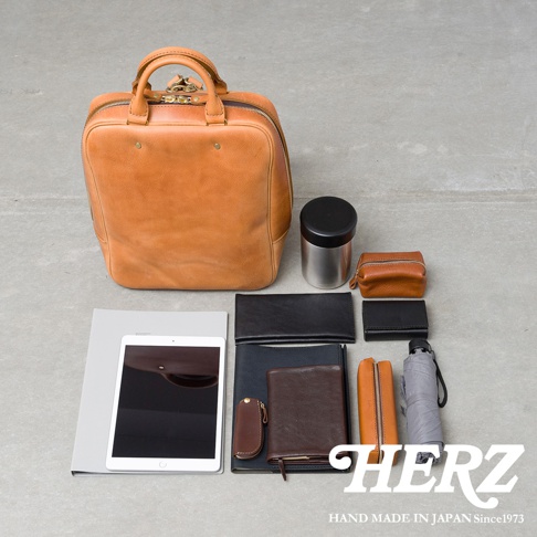 職人手作皮革Organ商務後背包 M-10，搭配多種配件，包含平板電腦、錢包、筆記本、化妝包、保溫瓶和摺疊傘。