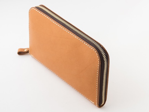 職人手作棕色皮革長夾，配有金色拉鍊和細緻縫線，左側有一個小巧的皮革拉環。