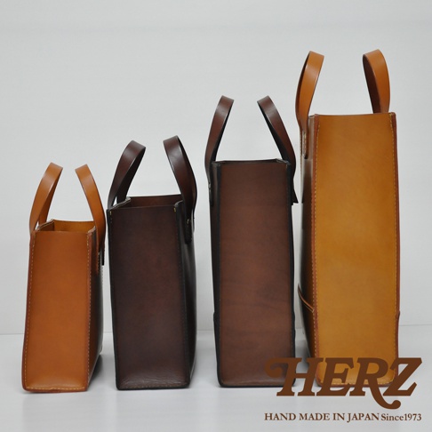 四個不同尺寸的職人手作皮革直式托特包，由左至右分別為淺棕色、深棕色、咖啡色與橘棕色，包款皆為直立式設計，搭配提把。
