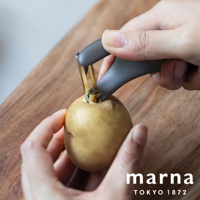 marna TOKYO 1872 品牌多功能削皮器，正用來削一顆馬鈴薯。
