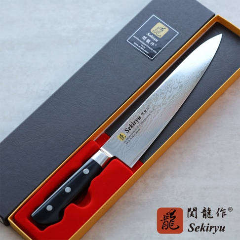 VG10不鏽鋼33層大馬士革牛刀，刀刃呈現獨特花紋，配備黑色三鉚釘手柄，置於黑色禮盒內。