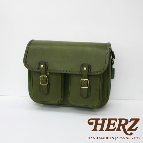 日本HERZ手工製作綠色皮革雙扣郵差包，正面有兩個翻蓋口袋和黃銅色搭扣。