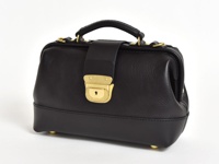 黑色皮革迷你口金包，附有金色鎖扣和提把，底部有四個金色腳釘。