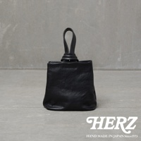 職人手作黑色皮革Organ單柄手提包，包身為柔軟的皮革材質，頂部有一個獨特的扭結提把設計，整體呈現簡約俐落的風格。