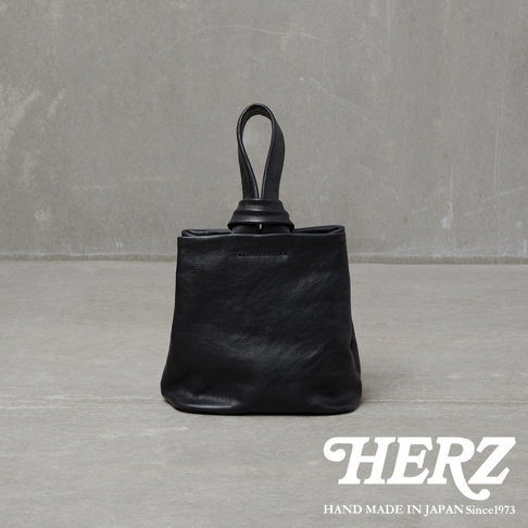 職人手作黑色皮革Organ單柄手提包，包身為柔軟的皮革材質，頂部有一個獨特的扭結提把設計，整體呈現簡約俐落的風格。