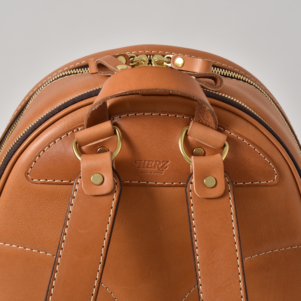 職人手作皮革多功能後背包 R-21，深棕色光滑皮革材質，附有雙向金色拉鍊、皮革提把、兩個連接肩帶的金屬環，以及肩帶上的金屬釦。