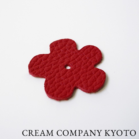 紅色皮革製成的五瓣花形零錢包吊飾，表面有細緻紋理，中心有一個小圓孔。