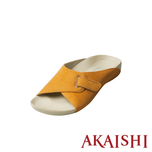 一隻橘黃色麂皮材質的指壓彈性室內拖鞋，鞋面為交叉設計，附有魔鬼氈可調整寬度。鞋墊為米白色，帶有按摩顆粒。