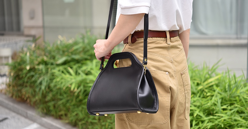 黑色皮革單肩兩用拱型手袋，配有可調節肩帶及金色金屬配件。