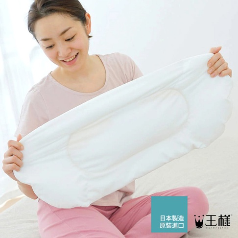 一名女子手持一個白色、材質柔軟的腰枕，腰枕呈現弧形，中央有明顯的凹陷設計，邊緣有波浪狀的裝飾。