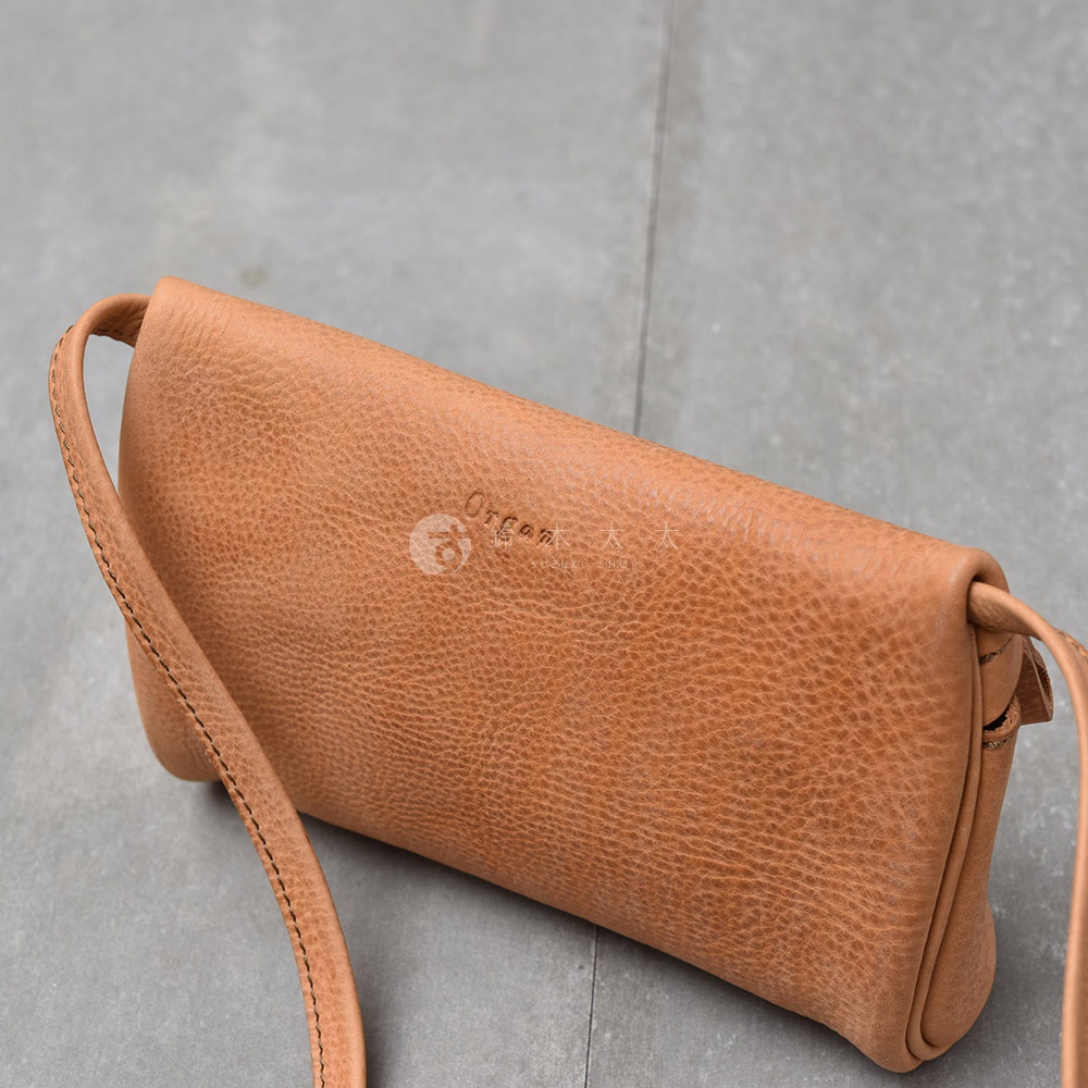 淺棕色皮革製成的斜背包，表面有細緻紋理，斜背包帶部分可見縫線細節。