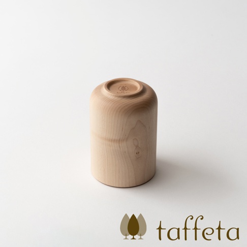 淺色楓木水杯，杯底朝上，呈現圓潤的曲線，木紋自然清晰，杯底刻有品牌標誌。