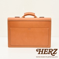 職人手作皮革機師箱 BC-31，採用 tan 色天然皮革，箱體結構方正，正面設有同色系皮革外袋，側邊與箱蓋邊緣皆以米色車線縫製，箱頂配有皮革提把及金屬扣環。