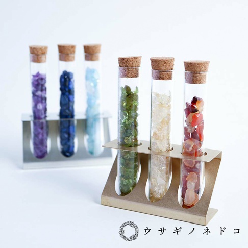 金屬試管瓶放置架，架上擺放著裝有不同顏色小石塊的玻璃試管瓶，瓶口均以軟木塞封存。