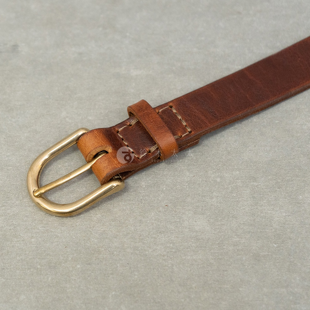 一條精緻的復古棕色皮革皮帶，搭配金色實心黃銅 D 型環扣，並有職人手作的縫線細節，整體呈現簡約而耐用的質感。