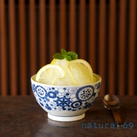 藍白日式飯碗，碗身飾有精緻的幾何圖案，盛裝著刨冰，上面點綴著檸檬片和薄荷葉，旁邊放著一個金屬湯匙。