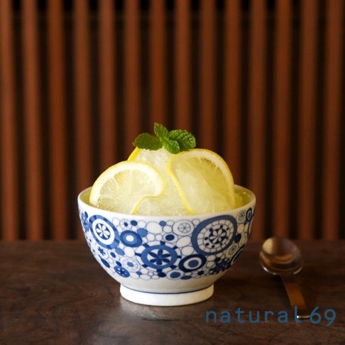 藍白日式飯碗，碗身飾有精緻的幾何圖案，盛裝著刨冰，上面點綴著檸檬片和薄荷葉，旁邊放著一個金屬湯匙。
