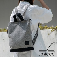 黑白格紋刺子織手提後背包，配有黑色提把與肩帶，底部為黑色純色拼接。