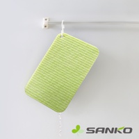 淺綠色帶有細緻紋路的迷你海綿洗衣板，側面有掛孔，正滴著水，懸掛在金屬桿上。