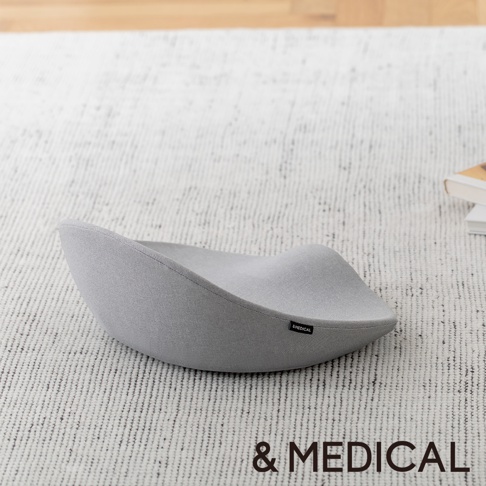淺灰色布面舒腰正姿座墊，呈現人體工學的曲線設計，底部有「& MEDICAL」標誌。