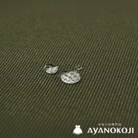 品牌Logo AYANOKOJI，搭配水珠在綠色斜紋布料上的特寫，展現布料的潑水機能。