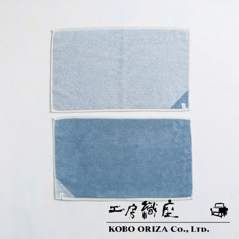 兩條棉麻混紡浴墊，一條為淺藍色，另一條為藍色，皆有白色滾邊。