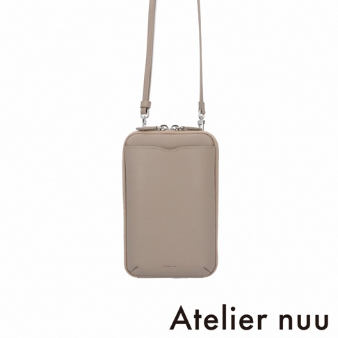 Atelier nuu 的 cote 皮革隨身手機包，呈現簡約俐落的長方形設計，採用質感細緻的淺灰褐色皮革製成，正面配有便利的收納夾層，並設有可拆卸的細肩背帶與金屬拉鍊開合。