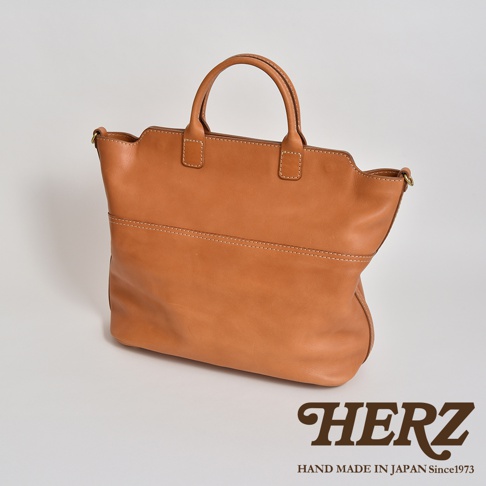 棕褐色皮革製成的大容量兩用托特包，包身線條簡潔，設有提把與雙邊肩帶，皮革表面有自然的紋理與縫線細節。