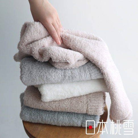 日本桃雪今治棉蕾超無撚蓬鬆浴巾疊放，手觸碰粉色浴巾
