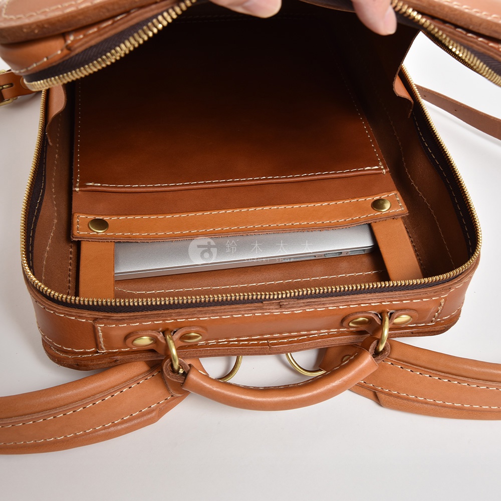 棕色皮革商務電腦後背包，內部有一個筆記型電腦夾層，展示了其手工縫製的細節和黃銅五金配件。