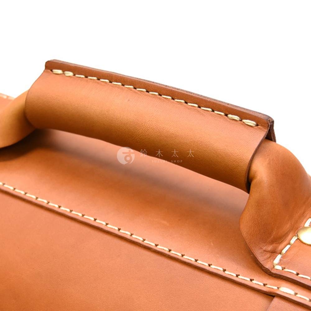 棕色皮革手提包的特寫，展示縫線工藝和圓形提把。