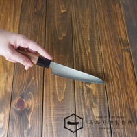 手持一把Chromax鋼水果刀，刀刃呈銀色，帶有波浪紋路。刀柄為胡桃木材質，末端為黑色。刀身下方是木紋桌面，右下角有「BABA CUTLERY WORKS SAKAI JAPAN 1916」的文字標誌。