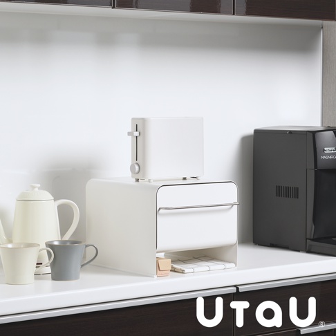 白色抽屜式多功能收納整理櫃，上方放置白色烤麵包機，櫃體前方有銀色金屬拉手，下方抽屜內有格紋布料，旁邊還有白色茶壺、米白色馬克杯和灰色馬克杯。