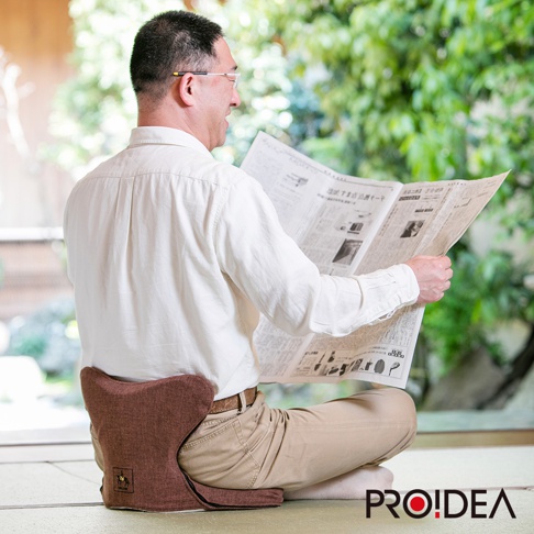 咖啡色馬鞍型正姿座墊，布質表面，符合人體工學設計，提供支撐。